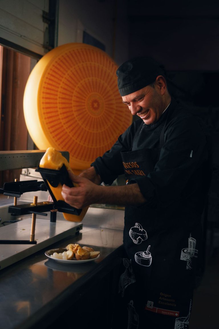 Cocinero preparando una raclette con Quesos de Suiza