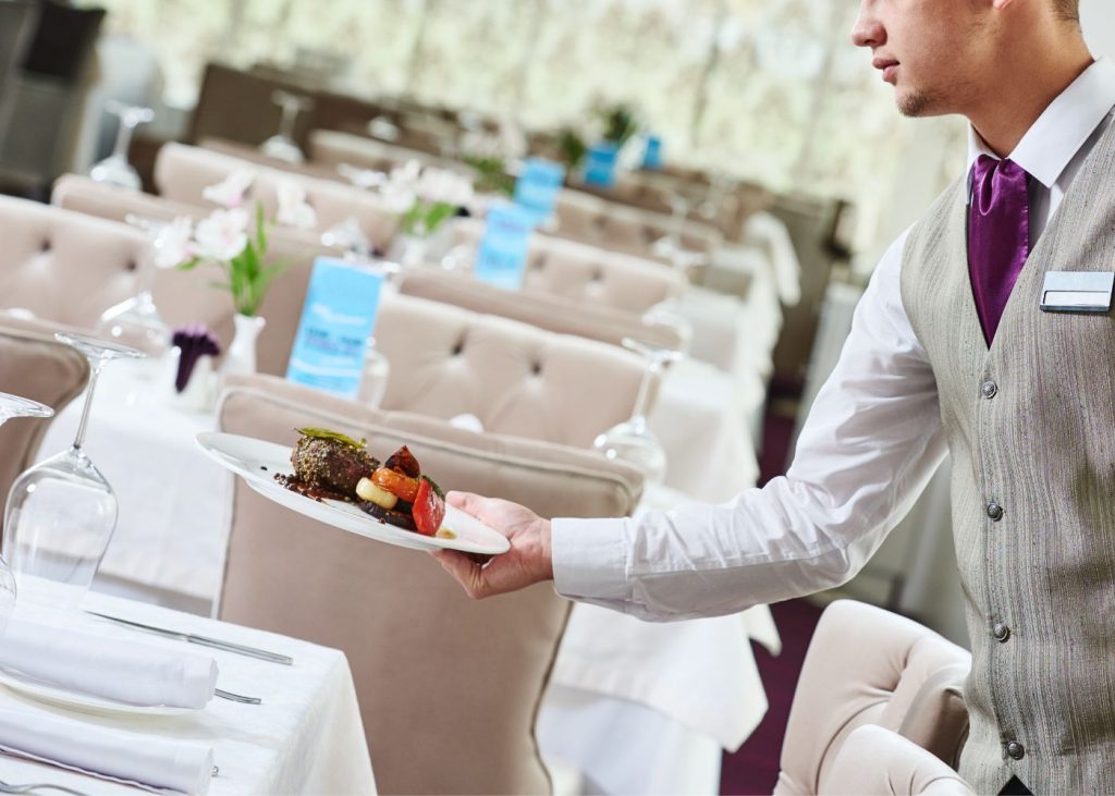 Un camarero sirve un plato en un restaurante